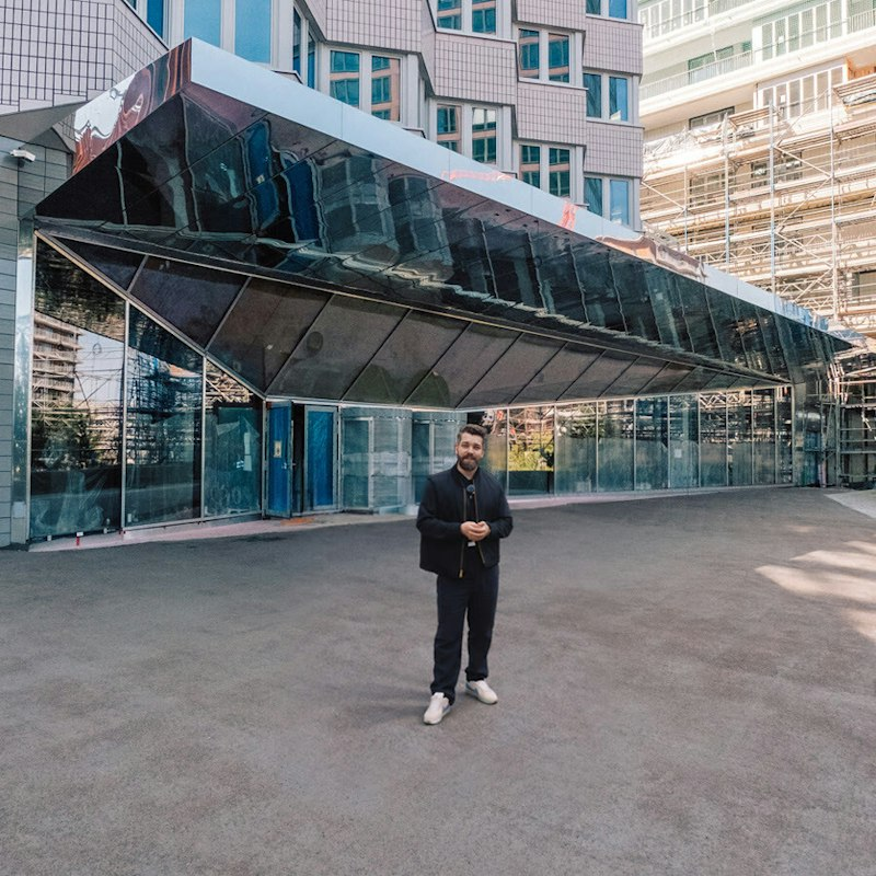 Hier ist die Übersetzung ins Englische: Standard / Descriptive Translation Maximilian Pohlmann is standing in front of the media facade of the UBS Digital Art Museum.